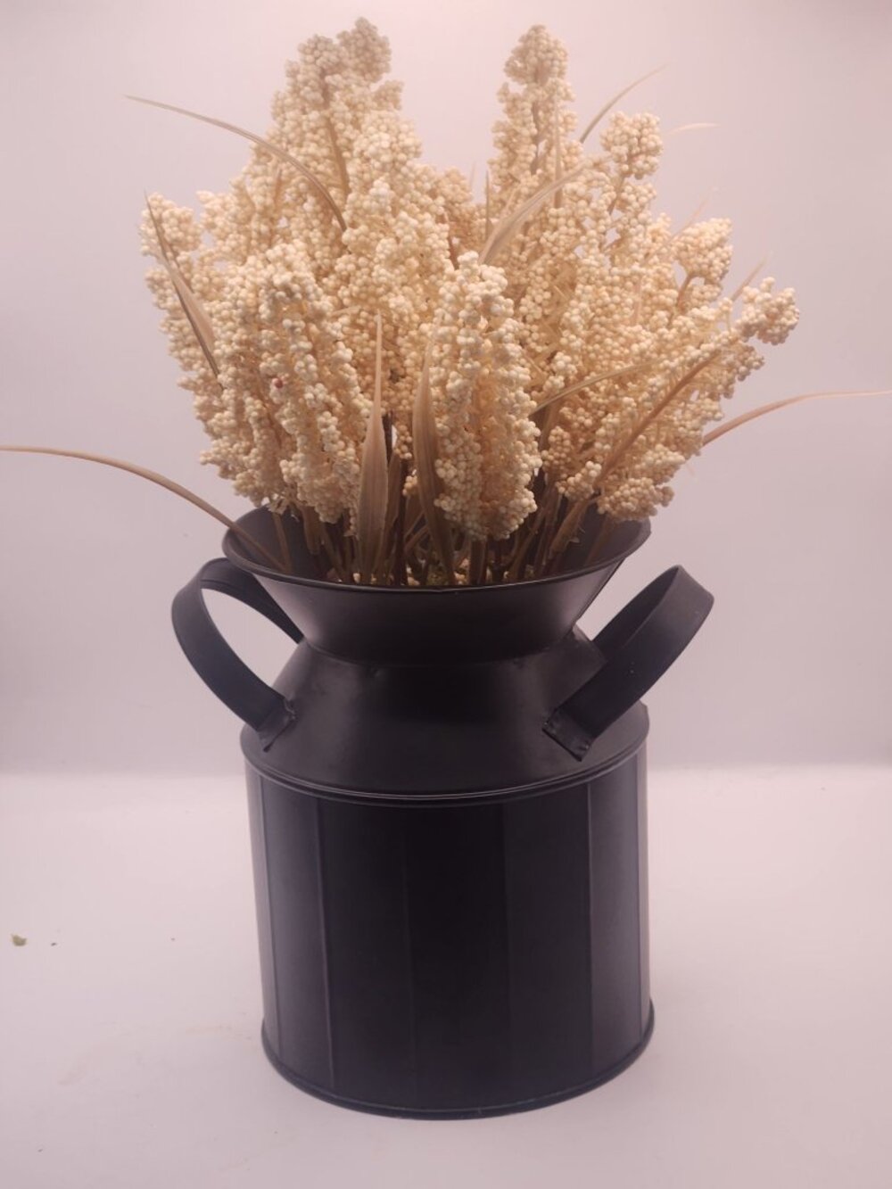 cream-colored flower sprays in a farmhouse-style metal milk jug vase.